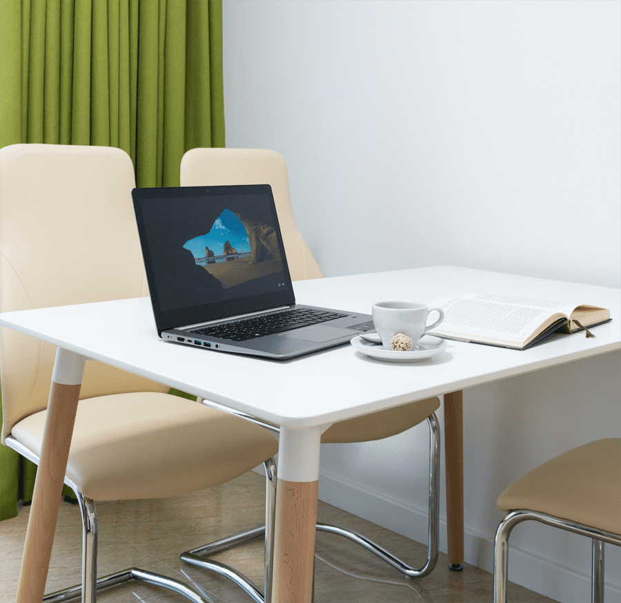 laptop on a white table with cup of tea next to it